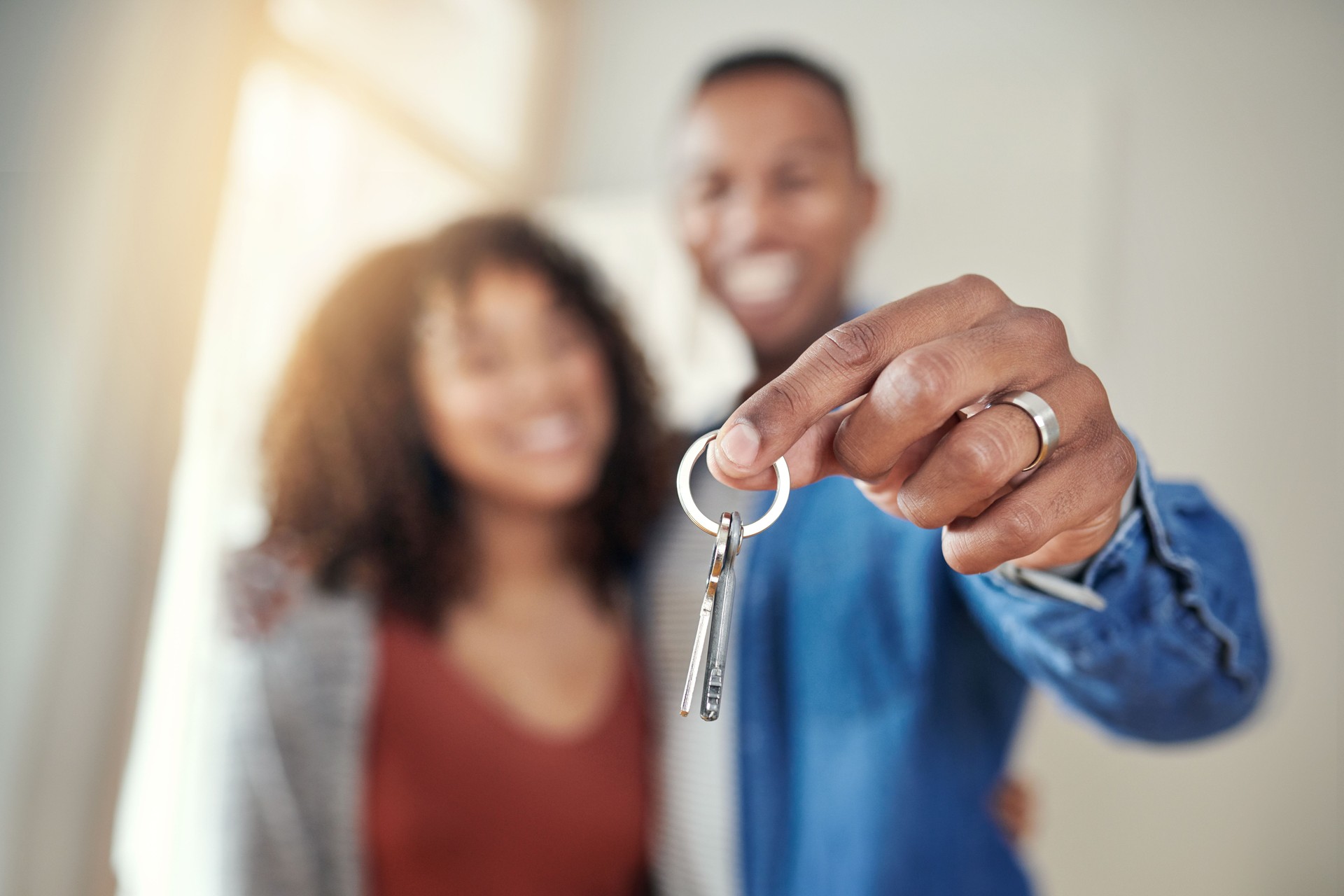 Defocused shot of a young couple holding the keys to their new home