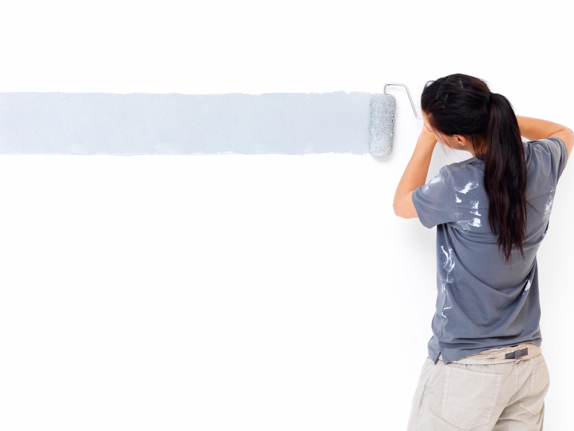 Back side view of a woman painting the wall