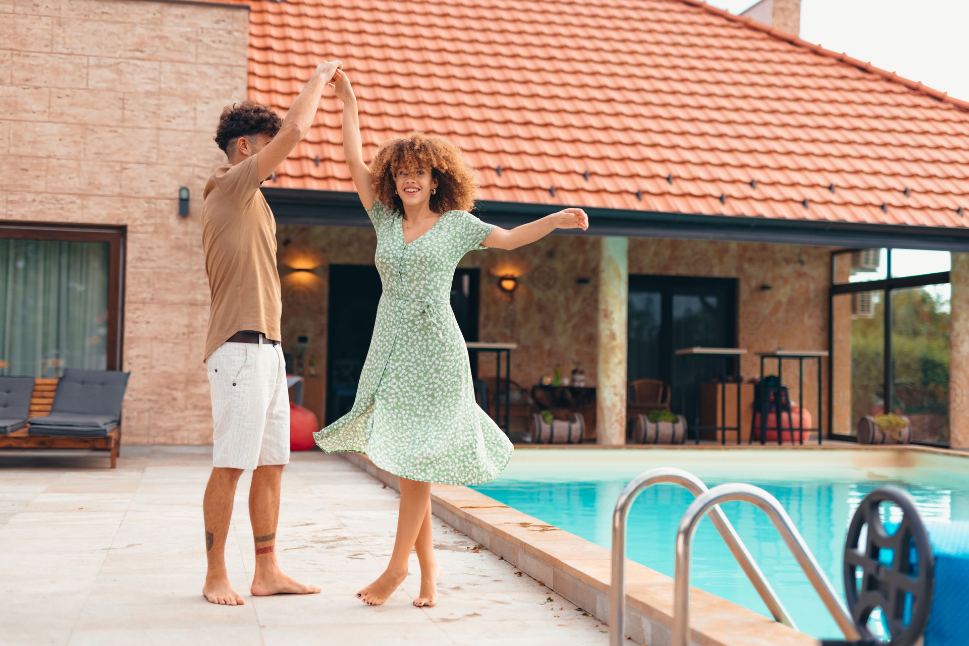 Happy couple dancing by the poolside of their house